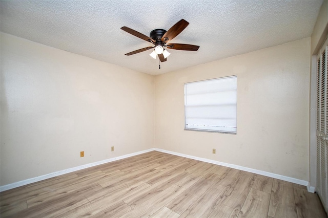 empty room with baseboards, a textured ceiling, light wood finished floors, and ceiling fan