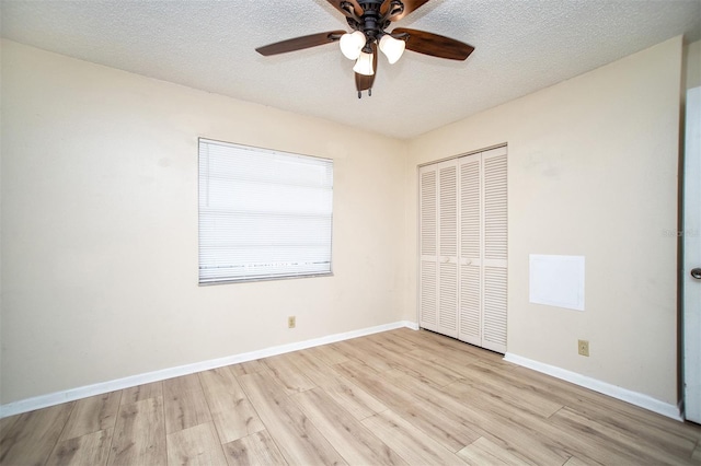 unfurnished bedroom with a closet, a textured ceiling, light wood-type flooring, and ceiling fan