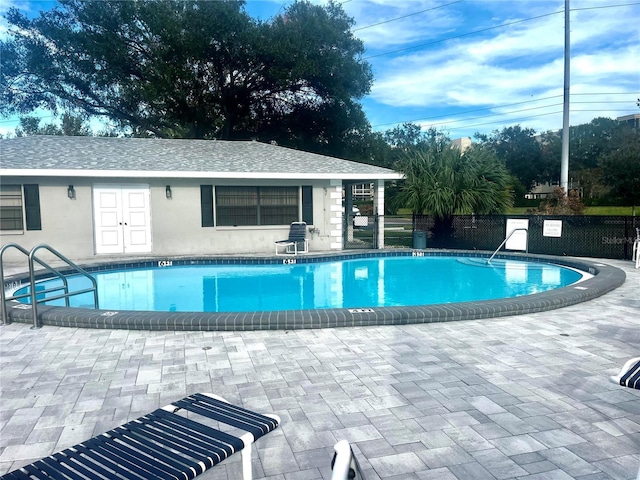 pool featuring fence, an outbuilding, and a patio area