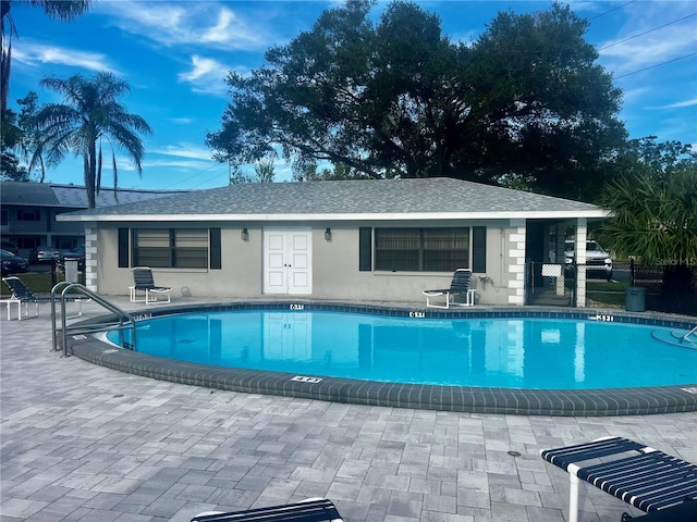 community pool with a patio area and fence