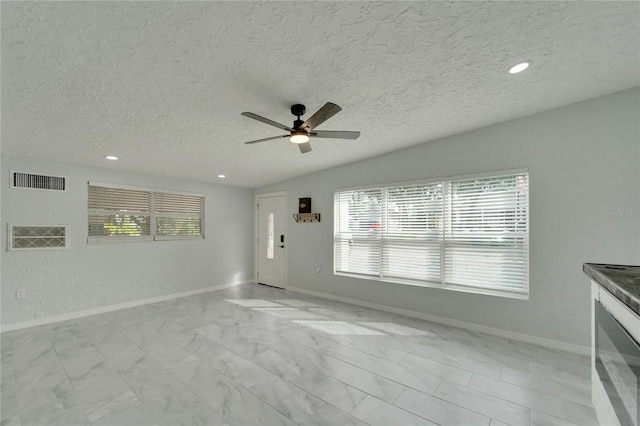 unfurnished living room featuring ceiling fan and a textured ceiling