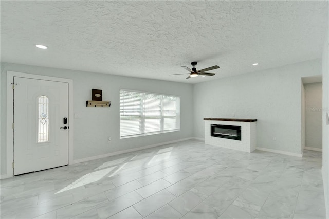 unfurnished living room with ceiling fan and a textured ceiling