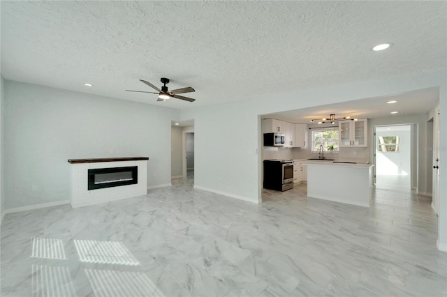 unfurnished living room with a textured ceiling, ceiling fan, and sink