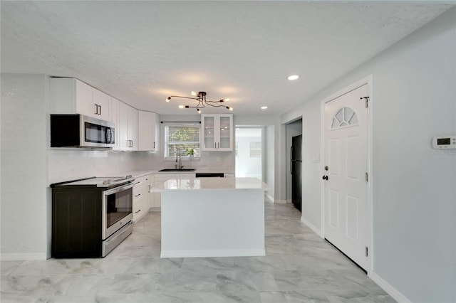 kitchen featuring a notable chandelier, a kitchen island, white cabinetry, and stainless steel appliances