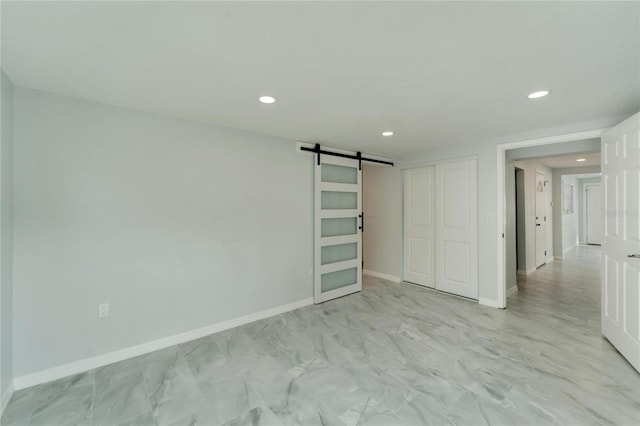 unfurnished bedroom with a barn door and a closet