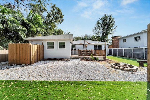 rear view of property featuring a fire pit, a deck, and a yard