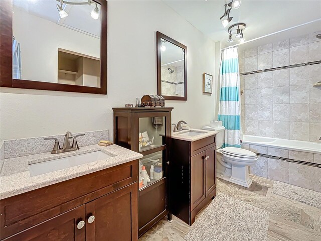 bathroom with two vanities, a sink, tiled shower / bath combo, and toilet