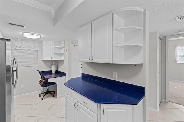 kitchen with stainless steel fridge, built in desk, white cabinetry, a textured ceiling, and light tile patterned flooring