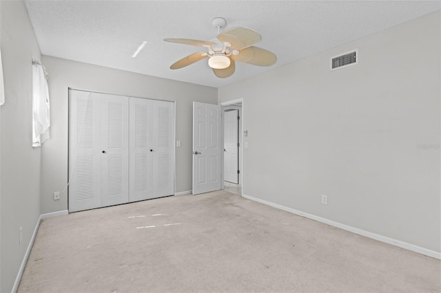 unfurnished bedroom featuring a closet, ceiling fan, light carpet, and a textured ceiling