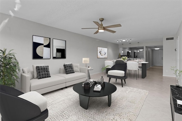 living room with ceiling fan and a textured ceiling