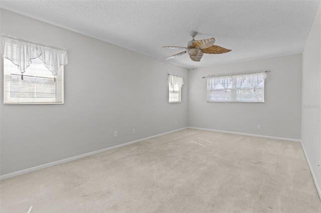 spare room with ceiling fan, a textured ceiling, and light colored carpet