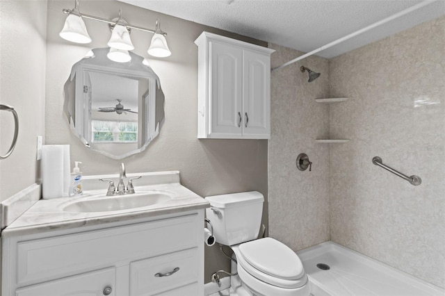 bathroom with vanity, toilet, a textured ceiling, and tiled shower