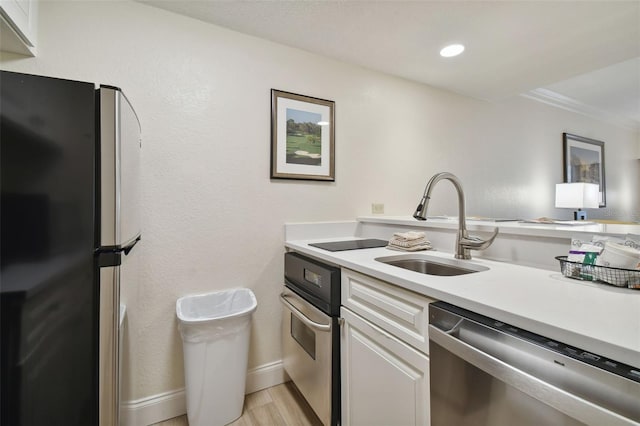 kitchen featuring sink, appliances with stainless steel finishes, light wood-type flooring, and white cabinets