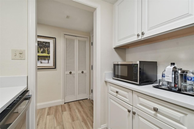 36750 US Highway 19 N Unit 09110, Palm Harbor, FL 34684 - kitchen featuring white cabinets, dishwasher, light countertops, light wood-style floors, and baseboards