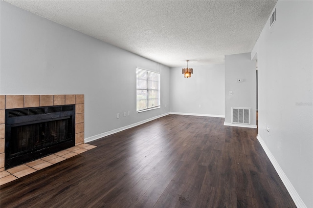14323 Hanging Moss Cir Unit 102, Tampa, FL 33613 - unfurnished living room featuring a tiled fireplace, wood finished floors, a chandelier, visible vents, and a textured ceiling