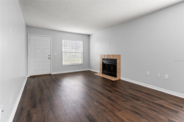 14323 Hanging Moss Cir Unit 102, Tampa, FL 33613 - unfurnished living room featuring a tile fireplace, dark wood-style flooring, a textured ceiling, and baseboards