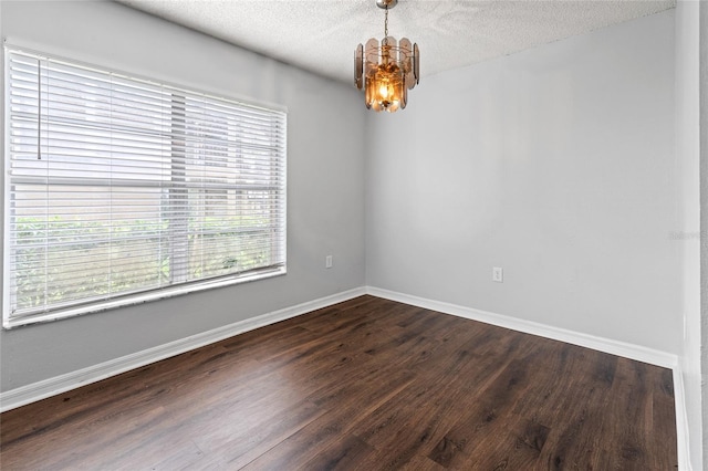 14323 Hanging Moss Cir Unit 102, Tampa, FL 33613 - unfurnished room featuring a textured ceiling, an inviting chandelier, dark wood-style flooring, and baseboards