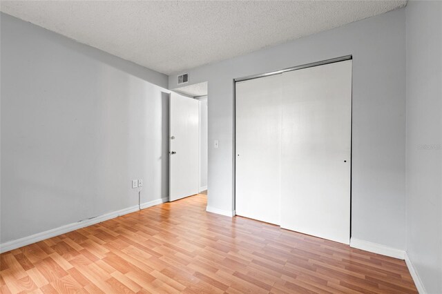 unfurnished bedroom with a closet, a textured ceiling, and light wood-type flooring