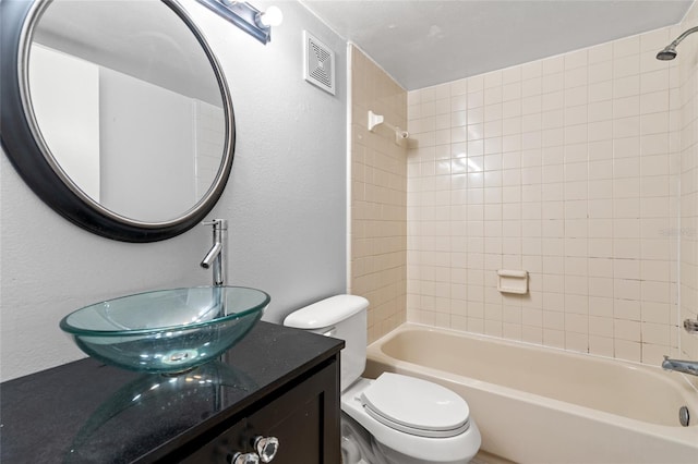 full bathroom featuring vanity, tiled shower / bath combo, and toilet