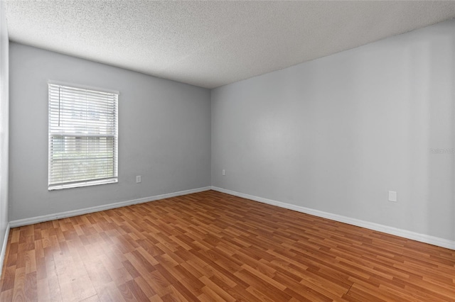 unfurnished room with wood-type flooring and a textured ceiling