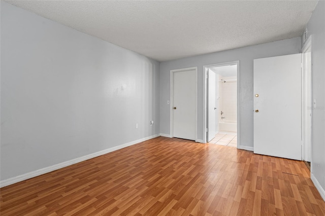 unfurnished room with light hardwood / wood-style flooring and a textured ceiling