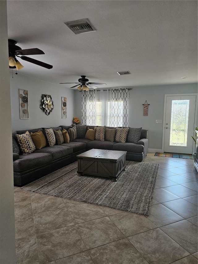 living room featuring tile patterned floors, ceiling fan, and a textured ceiling