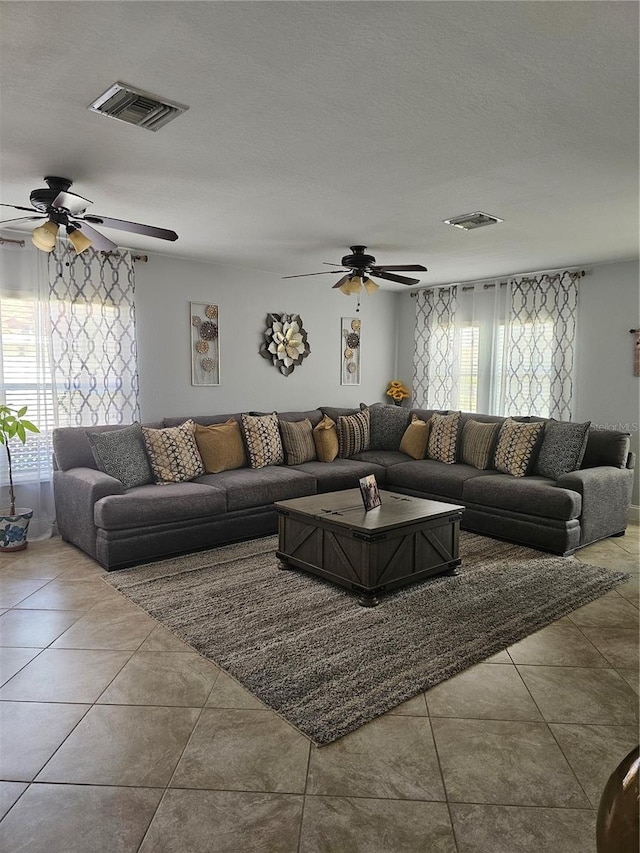 living room featuring light tile patterned floors, a textured ceiling, and a wealth of natural light