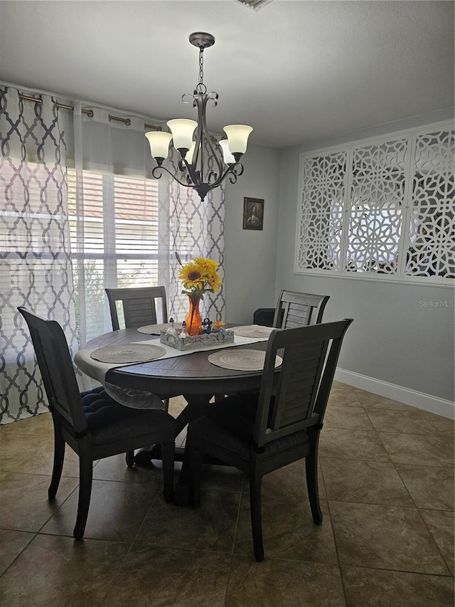 dining room with a notable chandelier and dark tile patterned floors