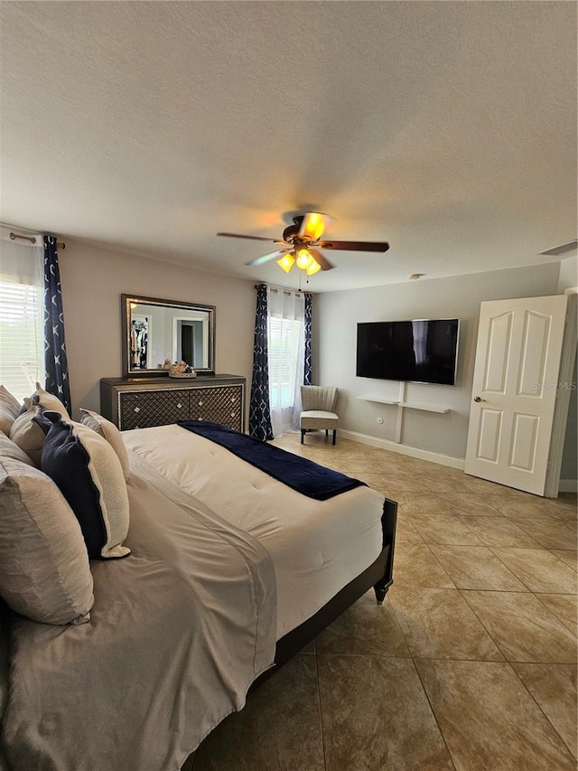 bedroom with light tile patterned floors, a textured ceiling, multiple windows, and ceiling fan