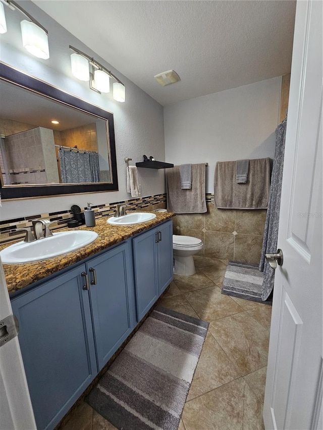 bathroom with tile patterned flooring, vanity, toilet, and a textured ceiling