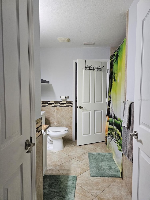 bathroom featuring tile patterned flooring, vanity, tile walls, and toilet