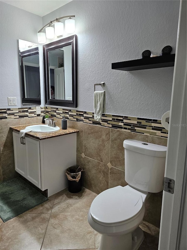 bathroom with vanity, toilet, and tile walls