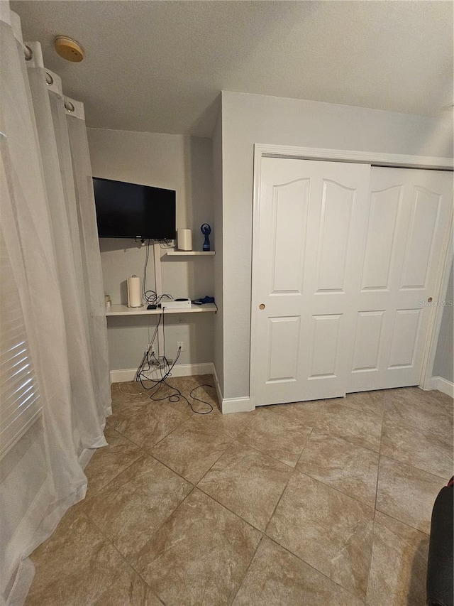 unfurnished bedroom with a closet, light tile patterned floors, and a textured ceiling