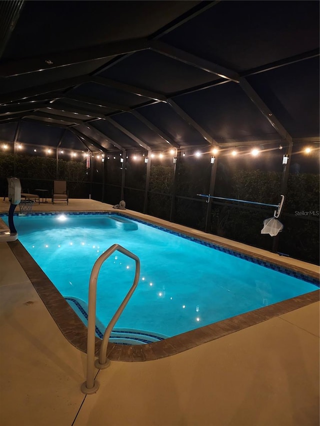 pool at twilight with a patio and glass enclosure