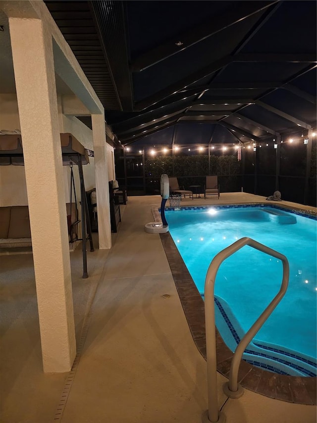 view of pool with glass enclosure and a patio