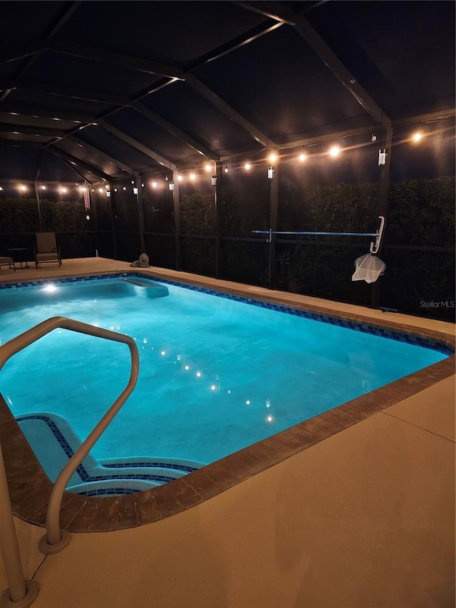 pool at twilight with a lanai and a patio area