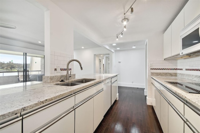 kitchen featuring a sink, dark wood finished floors, white appliances, and tasteful backsplash