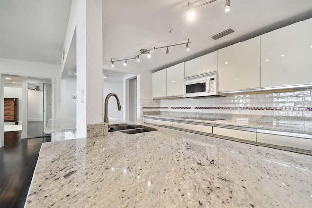 kitchen with light stone countertops, sink, and dark hardwood / wood-style flooring