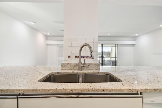 kitchen featuring recessed lighting, a sink, dishwasher, and light stone countertops