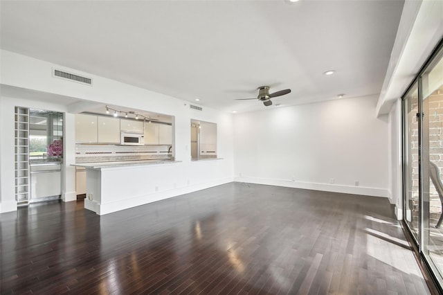 unfurnished living room with ceiling fan, visible vents, and dark wood-style floors