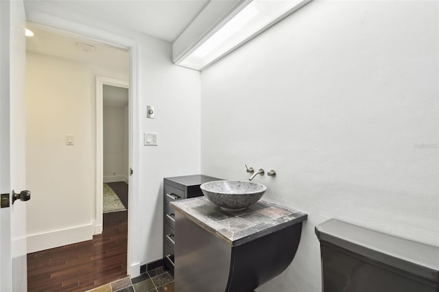 bathroom with toilet, vanity, and wood-type flooring