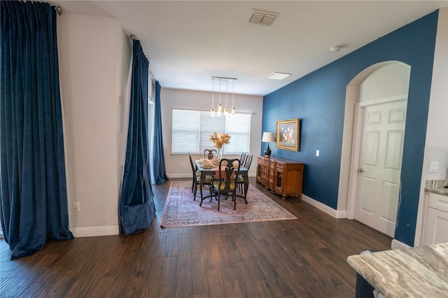 dining space with dark wood-type flooring and a notable chandelier