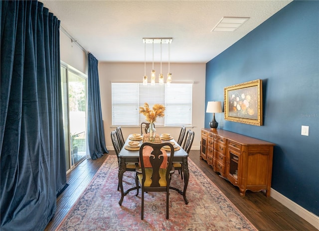 dining room with dark wood-type flooring and a textured ceiling