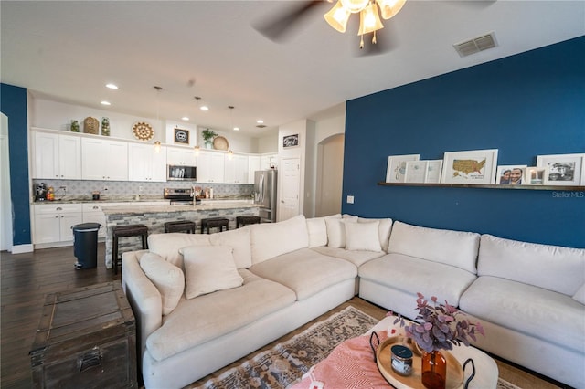 living room featuring ceiling fan and dark hardwood / wood-style flooring