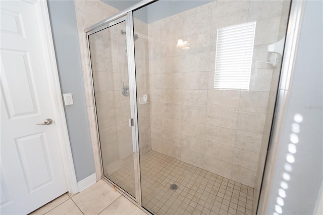 bathroom with a shower with door and tile patterned flooring