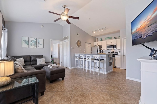 living room featuring ceiling fan, track lighting, lofted ceiling, and light tile patterned floors