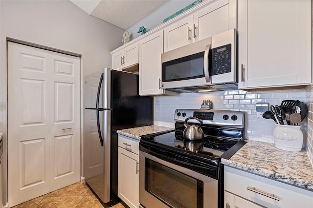 kitchen featuring light tile patterned floors, a textured ceiling, white cabinetry, light stone countertops, and stainless steel appliances