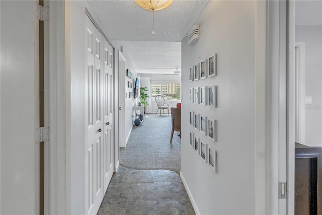 hall with a textured ceiling and carpet flooring