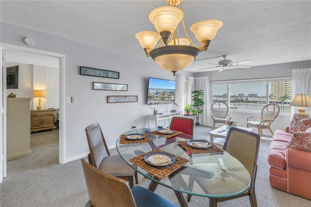 dining space featuring ceiling fan with notable chandelier, light colored carpet, and a textured ceiling