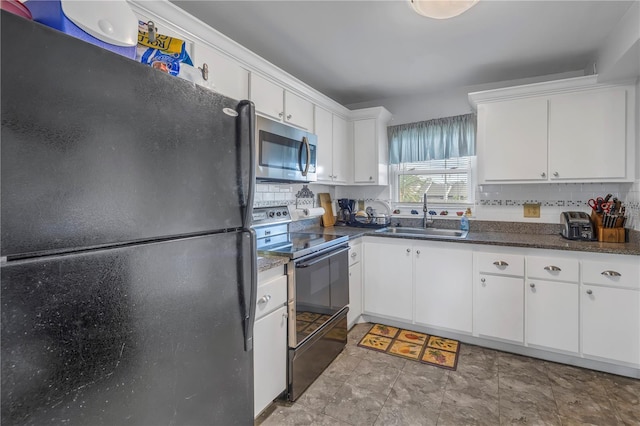 kitchen featuring black fridge, backsplash, range with electric cooktop, white cabinets, and sink